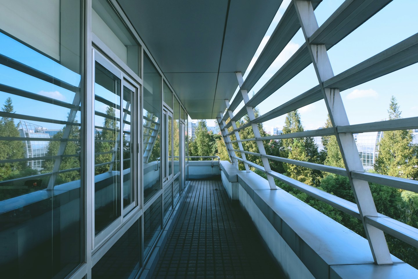 Modern balcony with tile flooring overlooking trees and buildings.