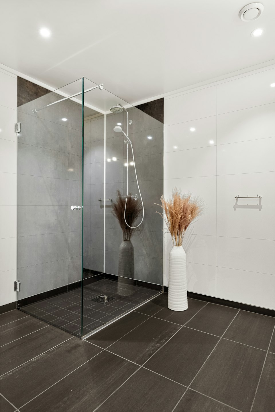Modern bathroom featuring a glass shower and decorative floor vase.